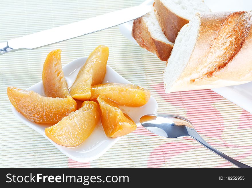 Baguette on plate, peach dessert, spoon and knife