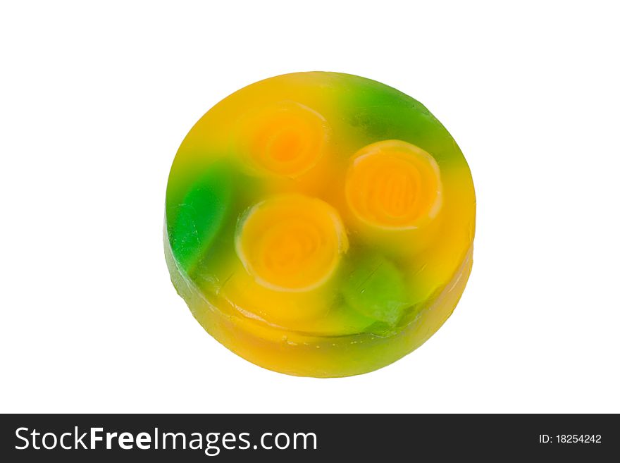 A brick of semi-translucent beauty soap, yellow and green with rose flowers visible inside. Round in shape, isolated on white. A brick of semi-translucent beauty soap, yellow and green with rose flowers visible inside. Round in shape, isolated on white.