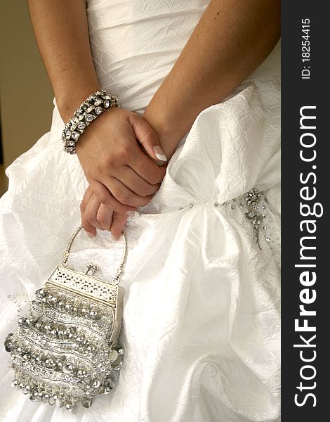 Close up of bride holding silver handbag with both hands. Close up of bride holding silver handbag with both hands