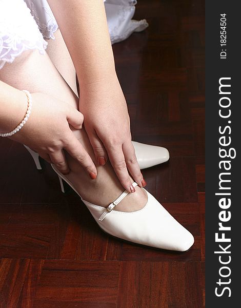 Bride touching her shoes against red wooden floor. Bride touching her shoes against red wooden floor