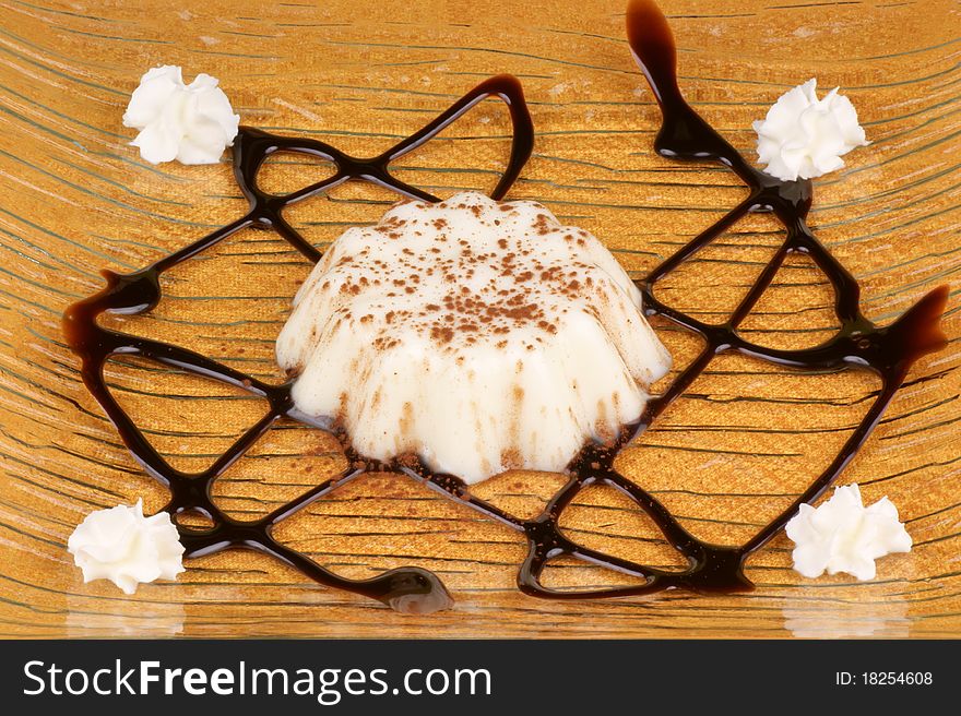 Panna cotta with cocoa powder served on a glass dish decorated with chocolate topping and whipped cream. Panna cotta with cocoa powder served on a glass dish decorated with chocolate topping and whipped cream.