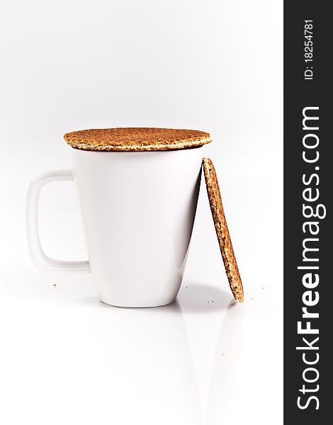 A white mug with 2 dutch waffles on a white backdrop. A white mug with 2 dutch waffles on a white backdrop