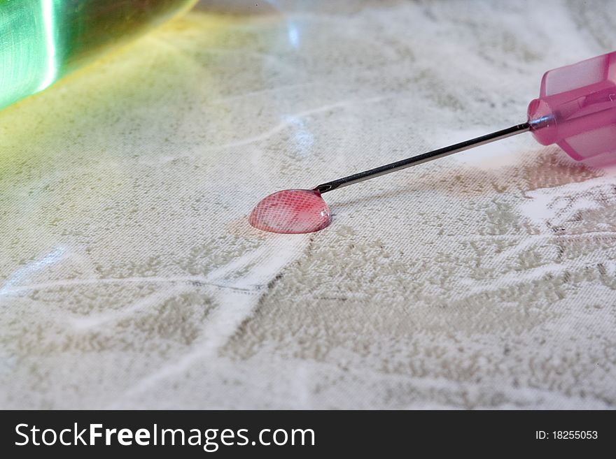 Pink liquid spill from a medical syringe.