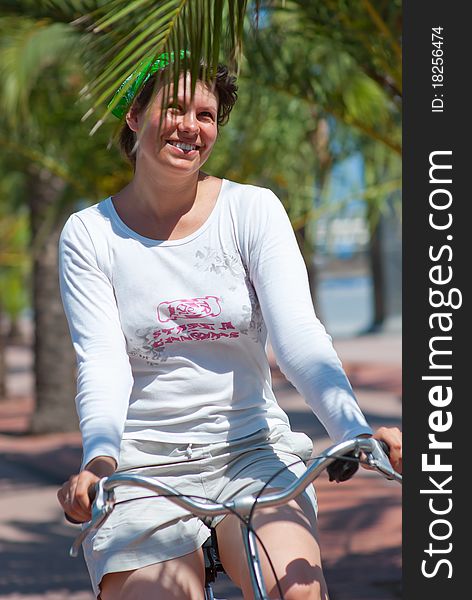 A young woman rides a bicycle through the palm trees