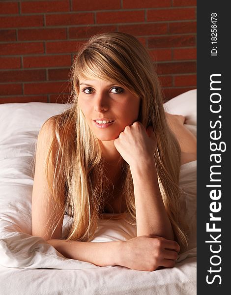 Beautiful young blond woman laying on her white bed. Beautiful young blond woman laying on her white bed