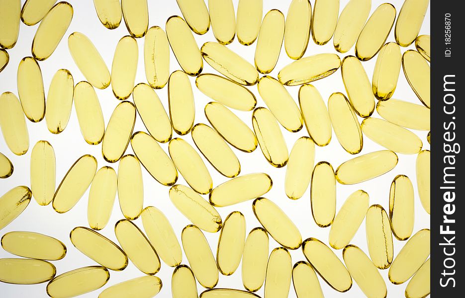Gold pills or capsules backlit on white for medical or science use. Gold pills or capsules backlit on white for medical or science use