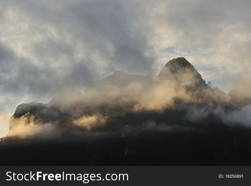 Silhouette of limestone mountain cover with mist in morning.