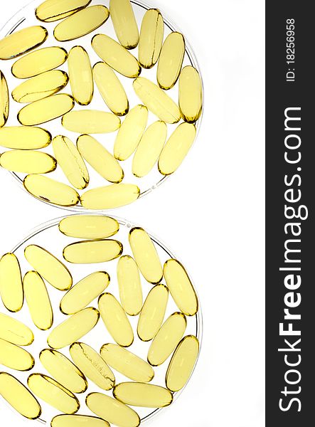 Gold pills or capsules backlit on white for medical or science use in petri dish. Gold pills or capsules backlit on white for medical or science use in petri dish