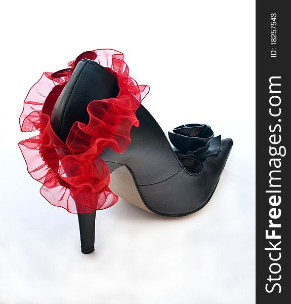 One black shoe with red garter on white background. One black shoe with red garter on white background