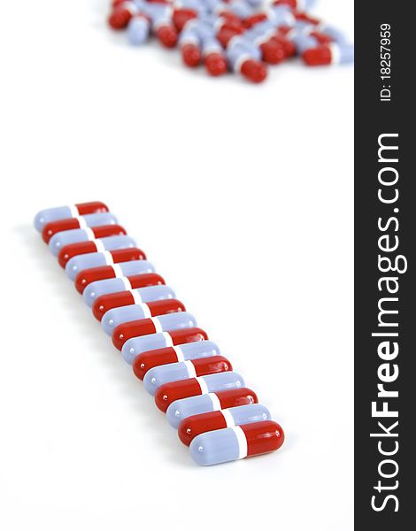 A row of blue and red pills with pills in the background on a white background. A row of blue and red pills with pills in the background on a white background.