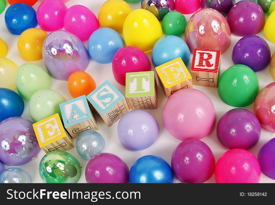 Childrens blocks spell Easter with colorful plastic eggs on a white background. Childrens blocks spell Easter with colorful plastic eggs on a white background.