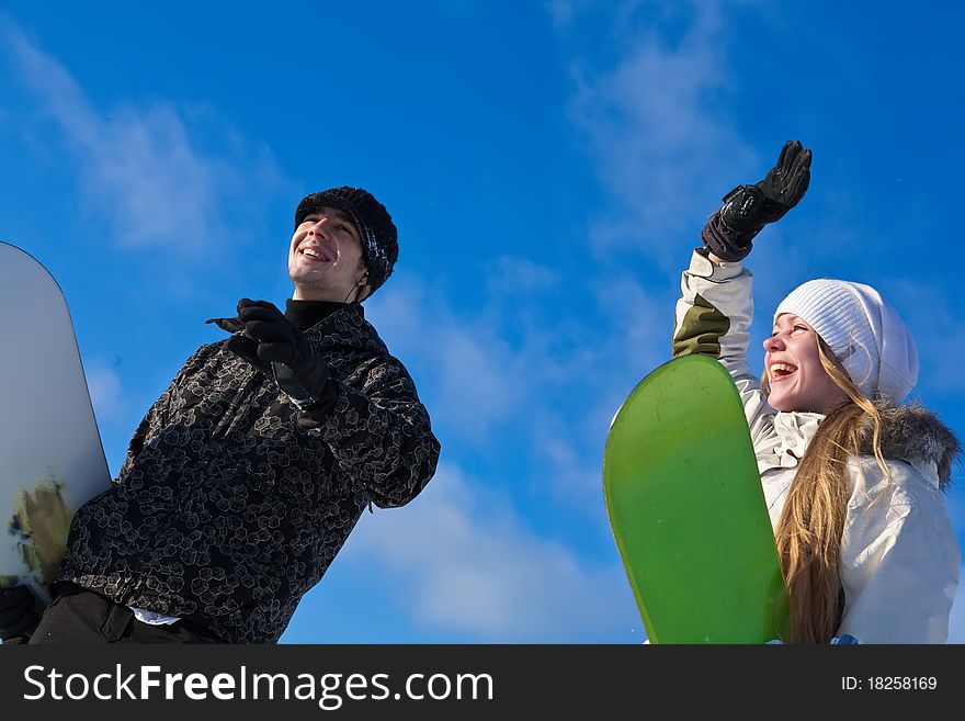 Young smiling couple with snowboards at winter day