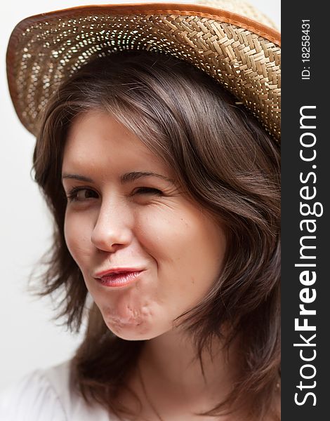 Winking young woman in straw hat on white background