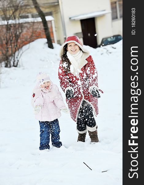 Young mother with her daughter playing with snow in park. winter day. Young mother with her daughter playing with snow in park. winter day