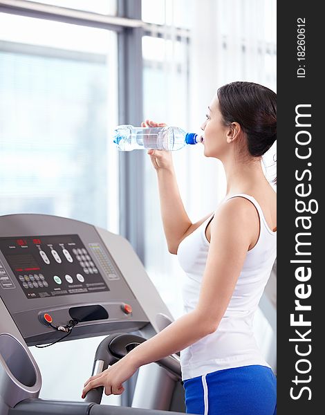 Young attractive girl drinks water in the fitness club