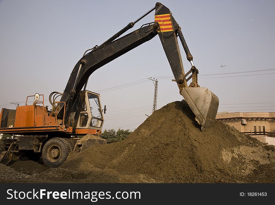 Excavator piling up the stones for road construction.