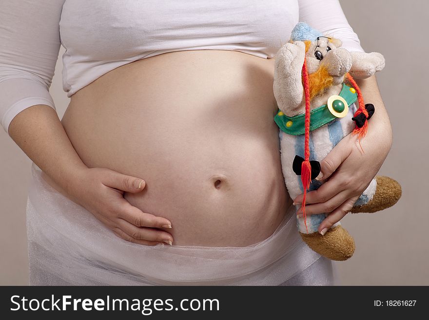 Pregnant mother holding baby plush toy on the left side