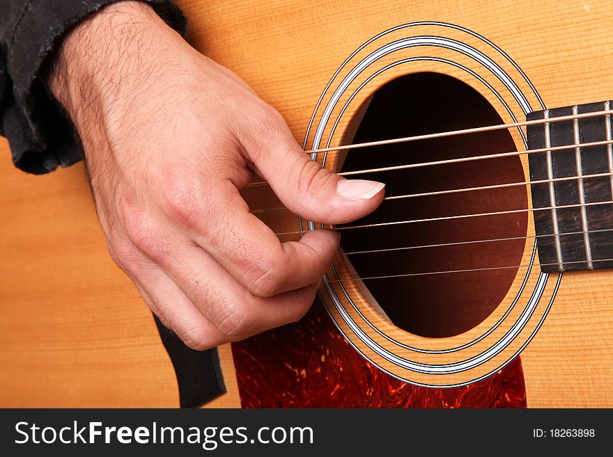 Hands of man playing an acoustic guitar wood