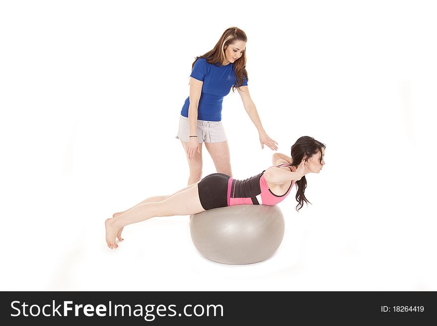 A woman is training another woman on a big ball. A woman is training another woman on a big ball.