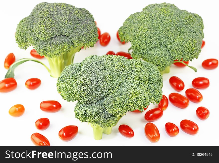 Three crowns of green vegetable standing upright with many small red fruit on white. Three crowns of green vegetable standing upright with many small red fruit on white.