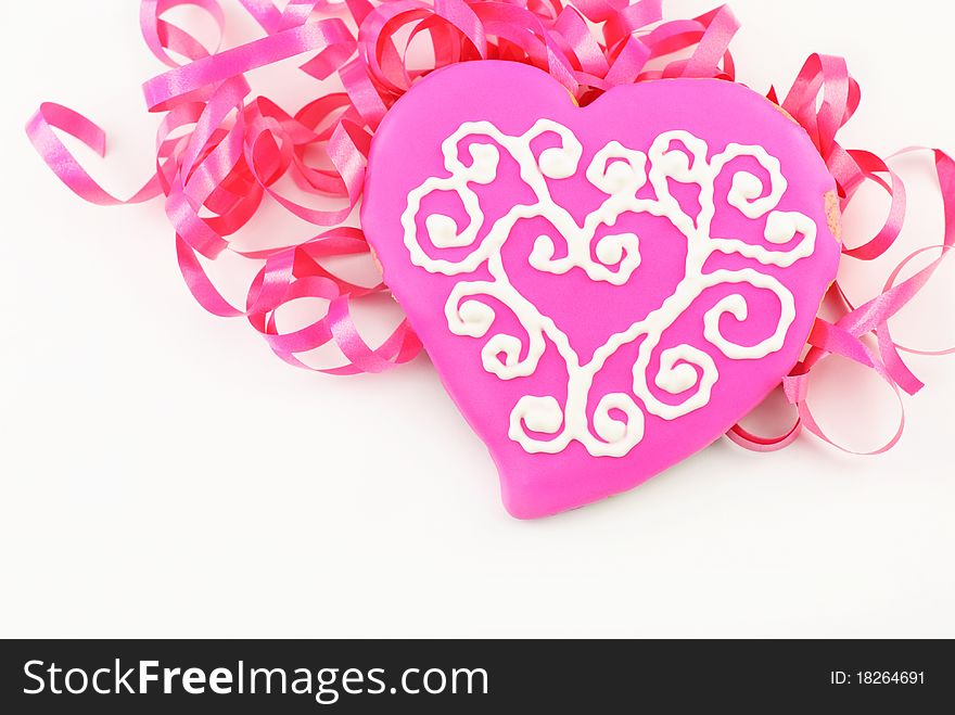 A delicious pink decorated Valentines cookie with ribbons and white background. A delicious pink decorated Valentines cookie with ribbons and white background