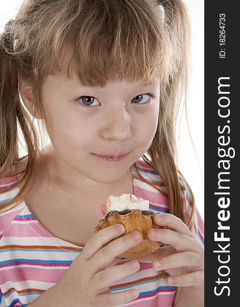 Small girl is eating cake. White isolated