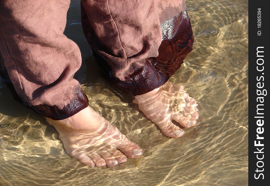 Barefoot woman standing in shallow water in seaside. Barefoot woman standing in shallow water in seaside.