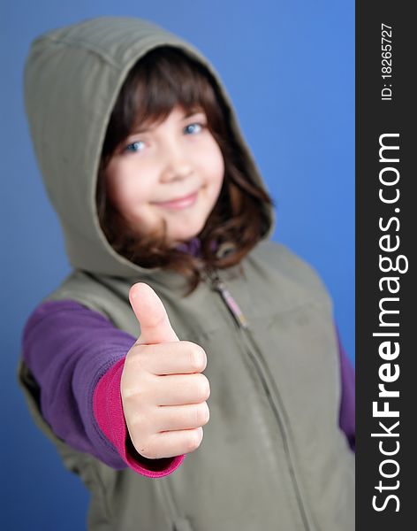 Little girl with thumb up on blue background