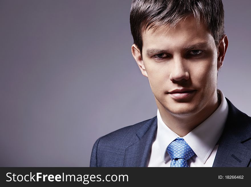 Young businessman in a business suit with a gray background. Young businessman in a business suit with a gray background