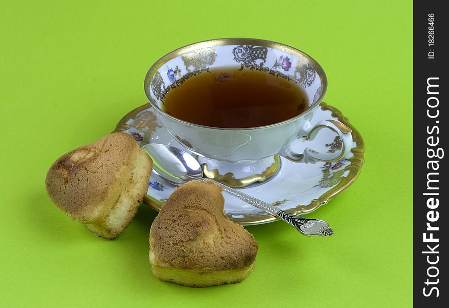 A cup of tea and biscuits on a green background. A cup of tea and biscuits on a green background