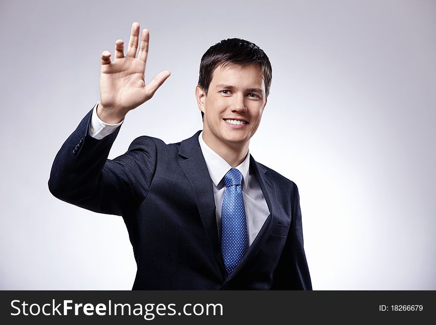 Attractive man in a suit with his hand raised on a gray background. Attractive man in a suit with his hand raised on a gray background