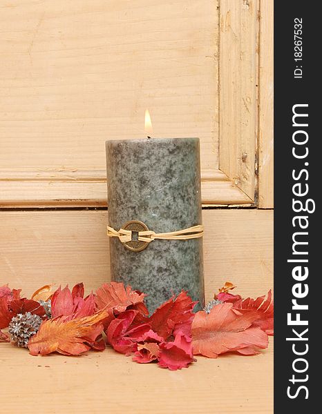 A single burning Feng shui candle with potpourri on a background of an old pine wood panel. A single burning Feng shui candle with potpourri on a background of an old pine wood panel