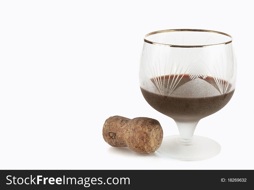 Glass of red wine and cork from a bottle on a light background. Glass of red wine and cork from a bottle on a light background