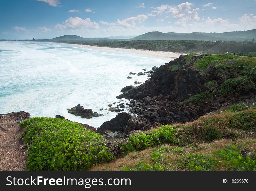 Australian seascape during the day with green hill in foreground (Cabarita Beach,NSW)