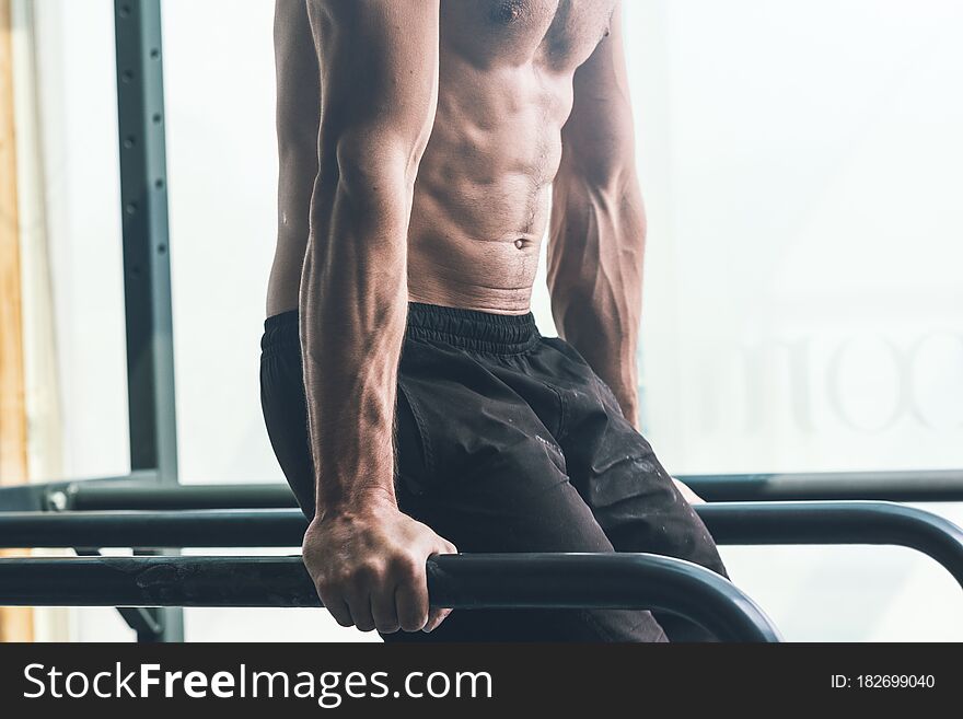 Muscular shirtless young man exercising at the gym on dip bars, fitness and sports concept. Muscular shirtless young man exercising at the gym on dip bars, fitness and sports concept