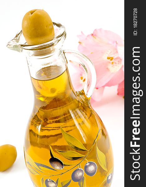 Fresh olive oil in a glass bottle on a white background