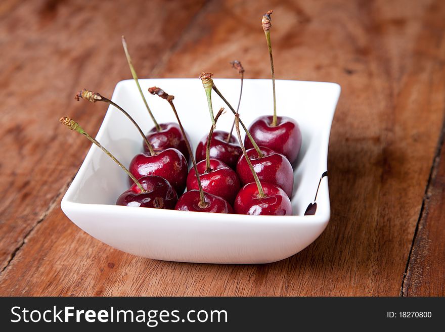 Cherries in bowl on wooden table