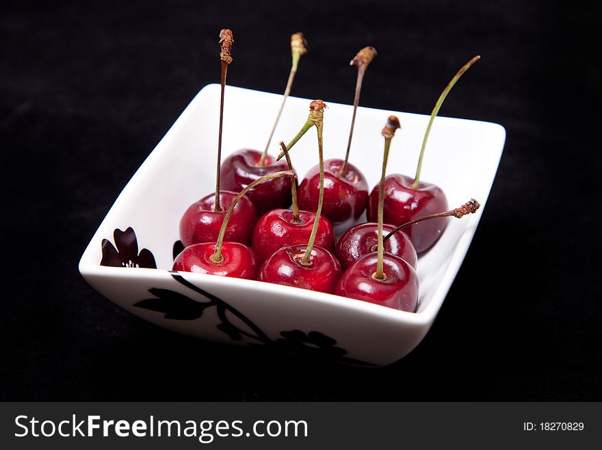 Cherries in bowl in black background