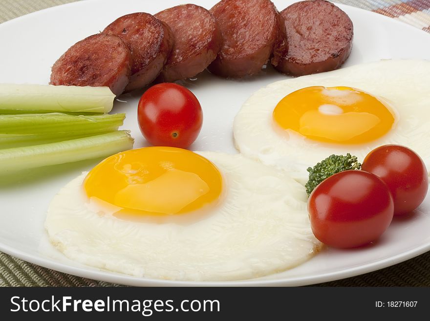 Fried eggs with fried sausage and vegetables.