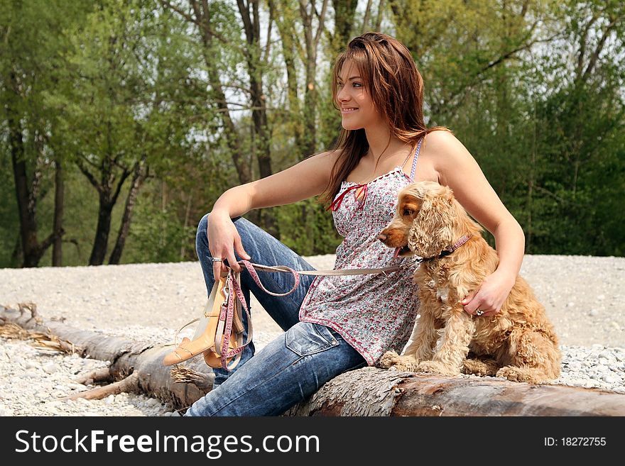 Beautiful brunette young woman sitting on a dead tree with her dog. Beautiful brunette young woman sitting on a dead tree with her dog