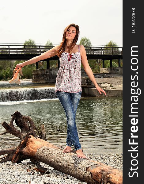 Young brunette woman walking barefoot outside at a river. Young brunette woman walking barefoot outside at a river
