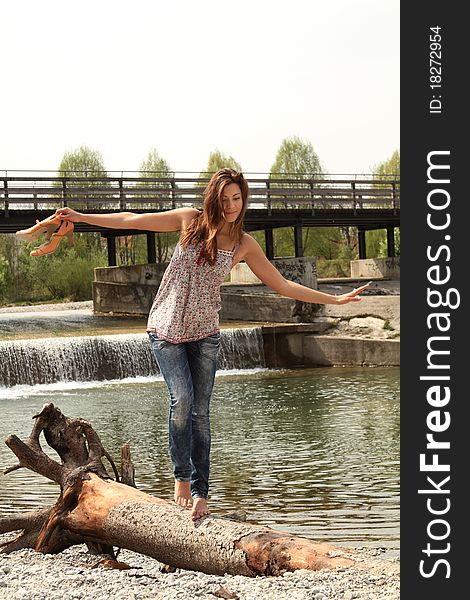 Young brunette woman walking barefoot outside at a river. Young brunette woman walking barefoot outside at a river