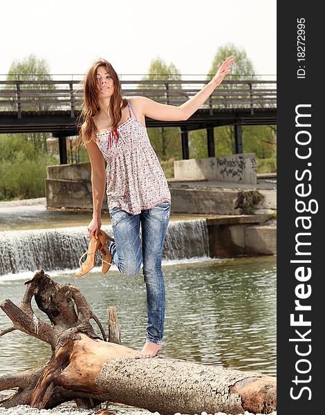 Young brunette woman walking barefoot outside at a river