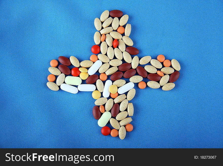 Pills on blue background in form of a cross. Pills on blue background in form of a cross