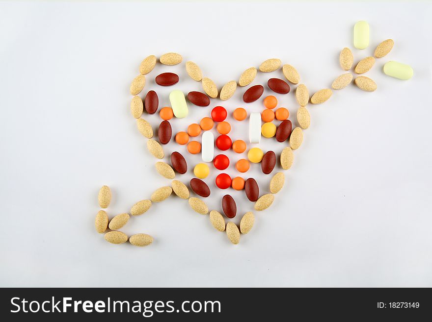 Pills in shape of love heartwitn arrow on white background. Pills in shape of love heartwitn arrow on white background