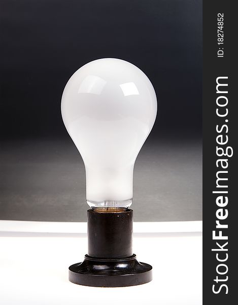 Large brushed electric incandescent lamp, against a dark background