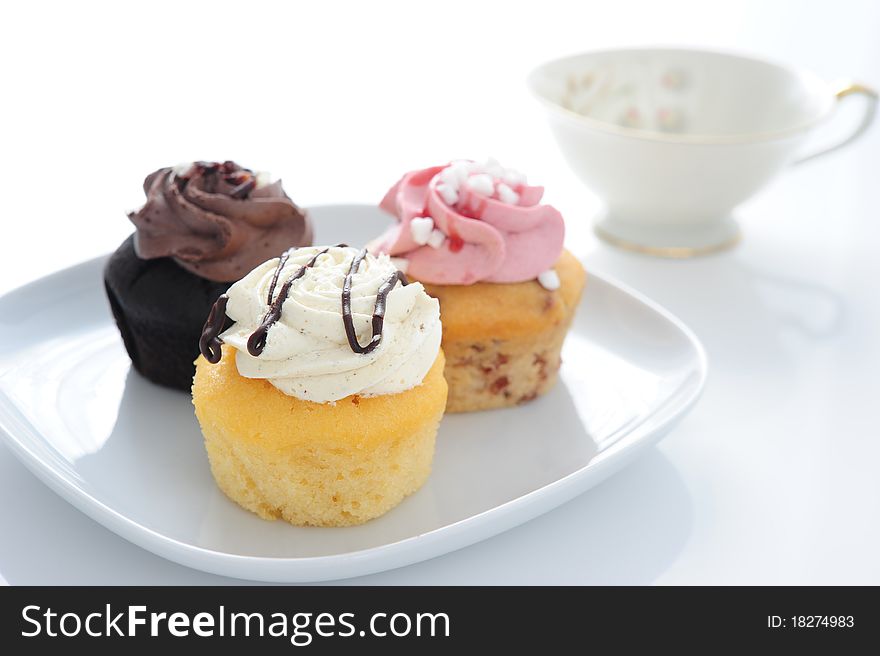 Three colored Muffin on a plate with a cup