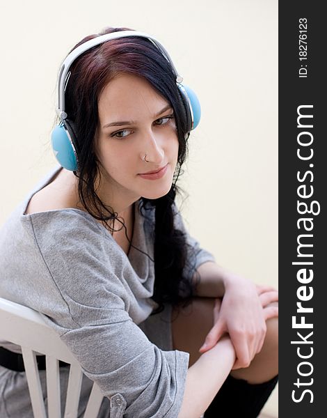 Caucasian dark haired woman with earphones on the chair