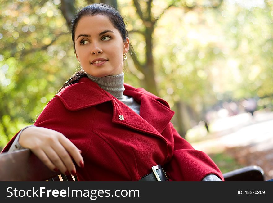 Young Caucasian woman sitting in a park on a wooden bench,