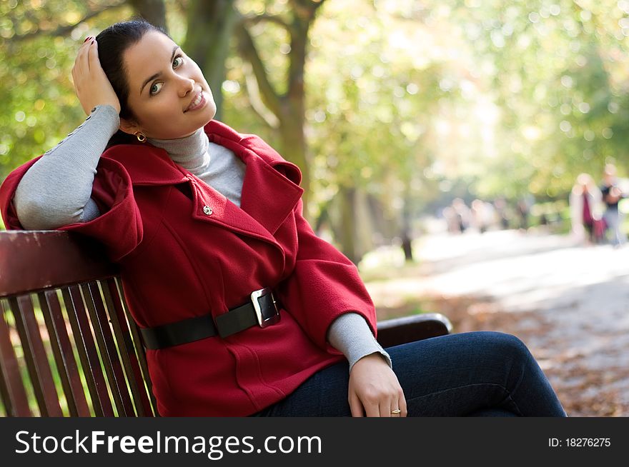 Woman Sitting In A Park On A Wooden Bench,